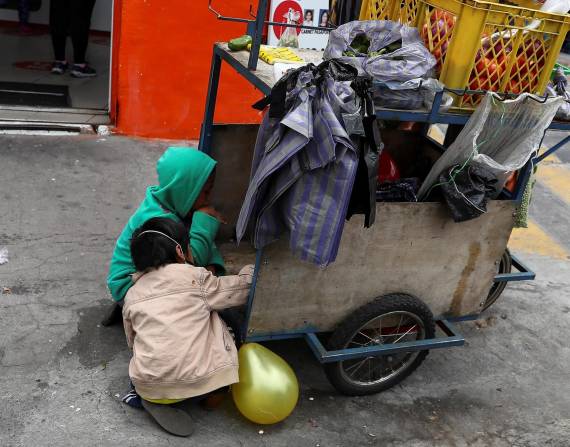 Niños acompañan a sus padres a trabajar con una carreta de productos vegetales en una calle de Quito, en una fotografía de archivo. EFE/José Jácome