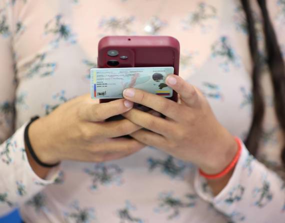 Una mujer con su celular y su cédula durante el simulacro de la consulta popular 2025.