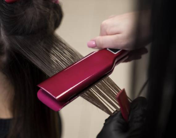 Imagen referencial del uso de una plancha alisadora de cabello.