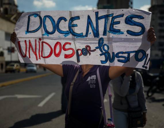 Una mujer sostiene un cartel durante una manifestación de profesores, frente al edificio del Ministerio de educación en Caracas (Venezuela).