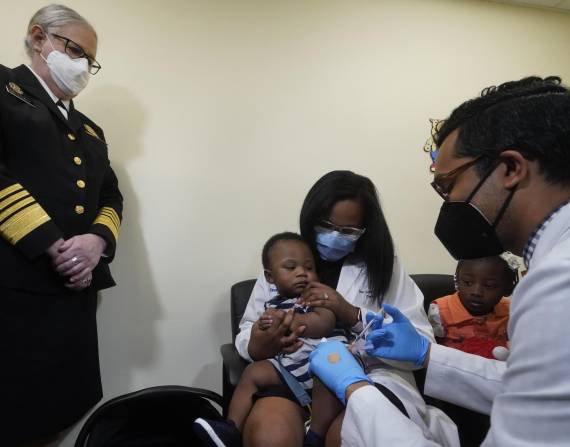 La pediatra Emy Jean-Marie, en el centro, sostiene a su hijo de nueve meses, Adedeji Adebayo, mientras es vacunado en el centro de salud Borinquen en Miami, Florida.