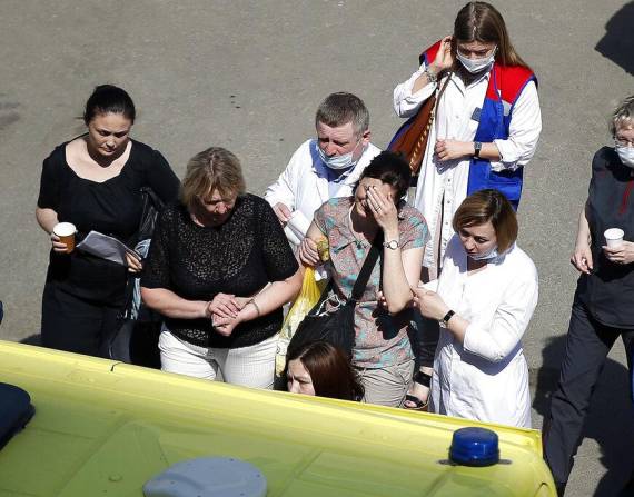 Empleados de salud y otras personas ayudan a una mujer para que suba a una ambulancia después de un tiroteo.