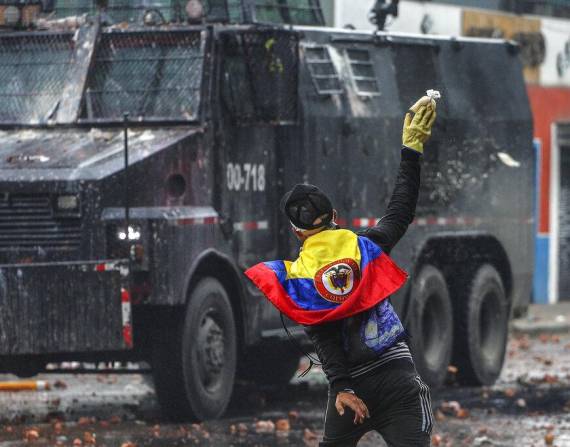 Un manifestante antigubernamental arroja una bolsa de pintura a un vehículo policial.