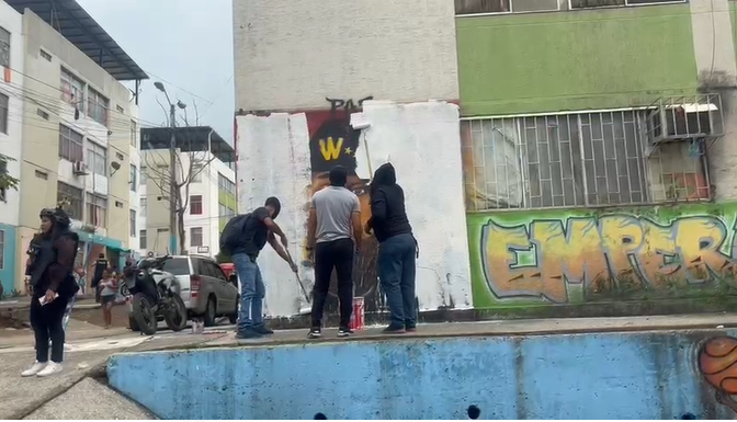 Imagen de civiles y policías borrando un mural de Los Tiguerones, que tiene el rostro de Willian Alcívar alias Comandante Willy, en Socio Vivienda 2, en Guayaquil.