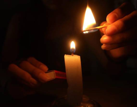 Imagen de una persona prendiendo velas ante la oscuridad de los apagones. Foto de archivo.