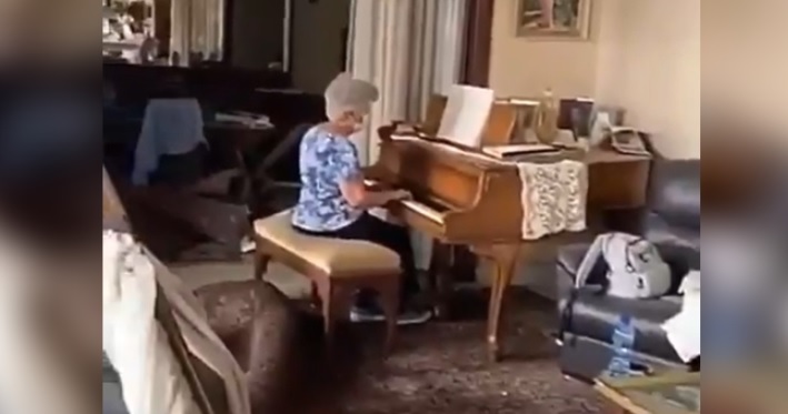 Mujer toca el piano entre ruinas de casa