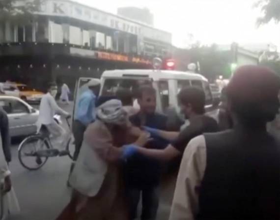 En una imagen tomada de un video, un grupo de personas brindan ayuda a una persona herida cerca del lugar de una explosión mortífera afuera del aeropuerto de Kabul.