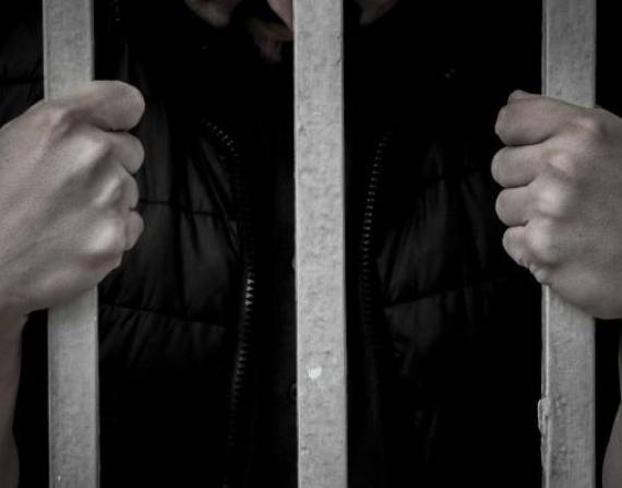 Imagen referencial de una persona detenida, tras las rejas.