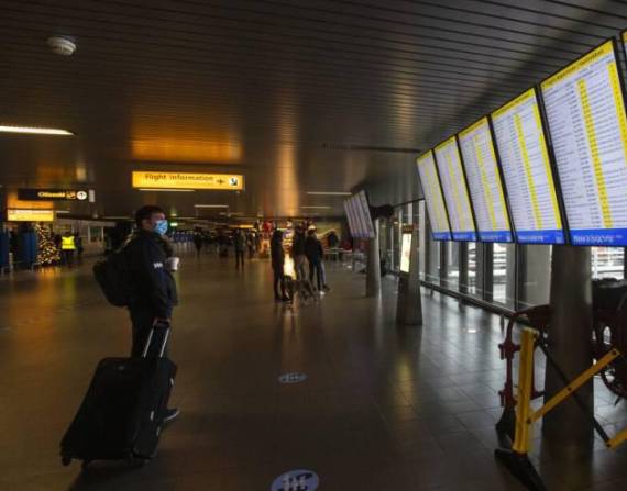 ARCHIVO - En esta imagen de archivo del viernes 18 de diciembre de 2020, un viajero con mascarilla mira las salidas de vueltos en el aeropuerto de Schiphol, cerca de Ámsterdam, Holanda. (AP Foto/Peter Dejong, Archivo)