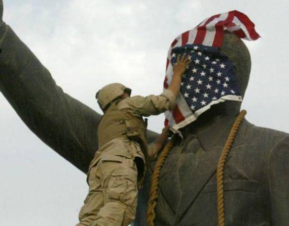 Un infante de marina estadounidense cubre el rostro de la estatua de Saddam Hussein en Bagdad días después de la invasión. La estatua luego fue derribada, convirtiéndose en una símbolo del derrocamiento del líder iraquí.