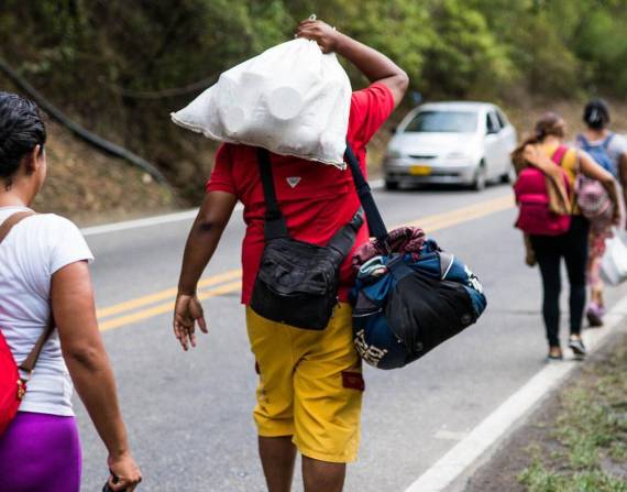 Migrantes venezolanos caminando en la vía.
