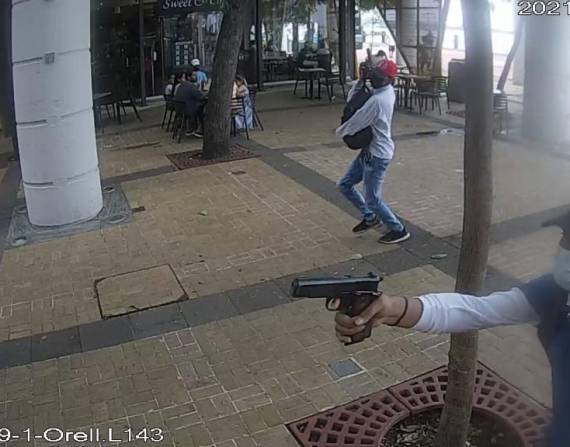 En la foto se observa a dos delincuentes con armas de fuego, cerca de las personas que recorrían la zona.