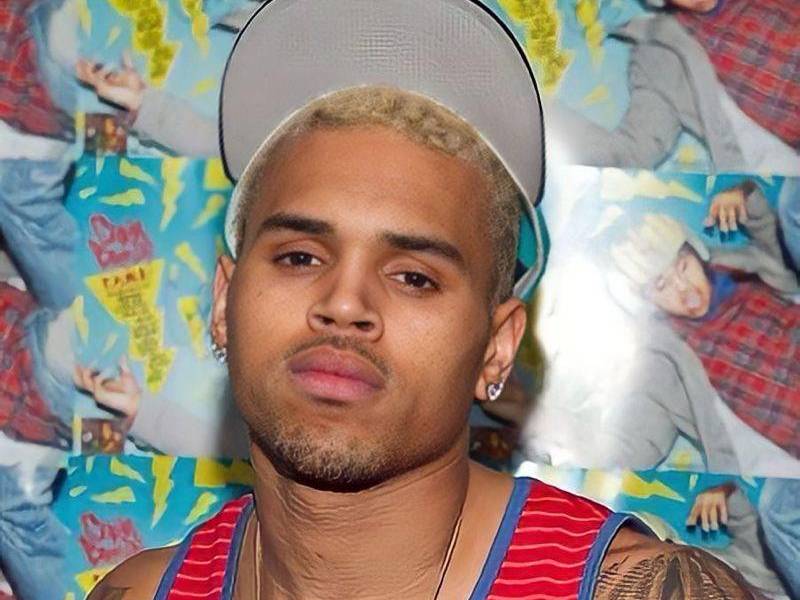 Fotografia de Chris Brown en una alfombra roja luciendo apático con gorra y camiseta roja.