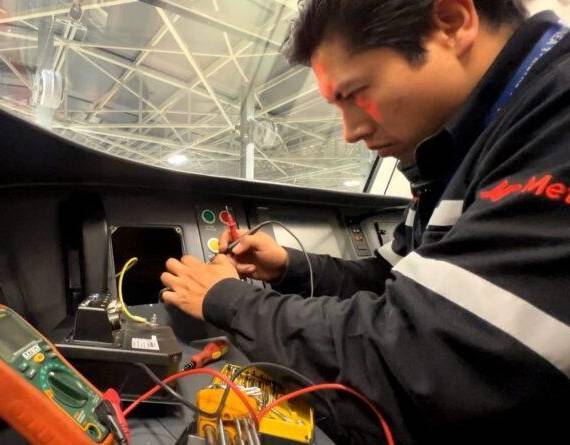Un técnico hace mantenimiento en un panel de control del Metro de Quito.