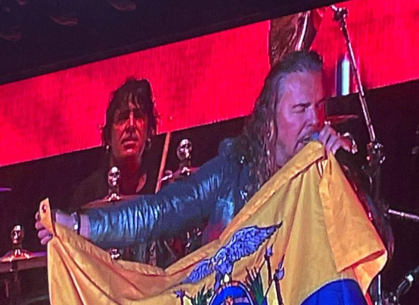 El vocalista de Maná, Fernando Olvera, sostiene la bandera de Ecuador.