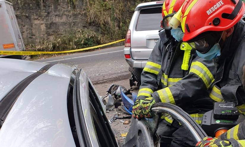 Momento en el que los bomberos tratan de abrir la puerta de un carro chocado.