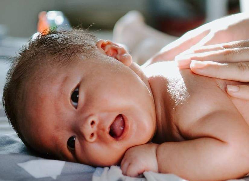 Fotografia de bebe recostado boca arriba viendo a la camara.
