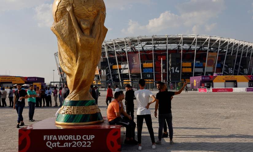 People pose for photos next to a giant replica on the World Cup trophy in front of Stadium 974 on November 18, 2022 in Doha, Qatar, ahead of the Qatar 2022 World Cup football tournament. (Photo by David GANNON / AFP)