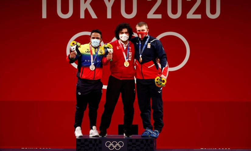 El catarí Fares Ibrahim Saed Hassouna El-Bakh (c-oro), el venezolano Keydomar Giovanni Vallenilla Sanchez (i-plata) y el georgiano Anton Pliesnoi (d-bronce) celebran en el podio de la prueba de levantamiento de pesas masculino de 96 kg durante los Juegos Olímpicos 2020, este sábado en el Foro Internacional de Tokio (Japón). EFE/José Méndez