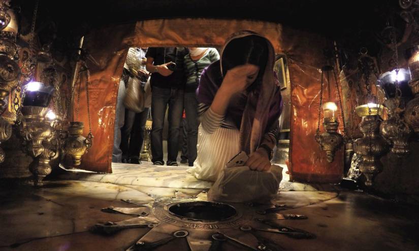 Una mujer se santigua junto a la estrella que marca el lugar en el que nació Jesucristo según la tradición cristiana en la gruta de la iglesia de la Natividad en Belén, Palestina.