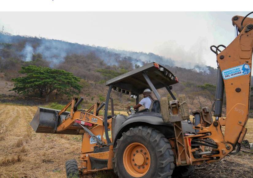 Una retroexcavadora abre trochas para facilitar el acceso de los bomberos a la zona.
