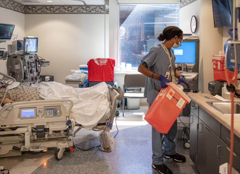 Un trabajador de la salud lleva un recipiente con desechos biológicos a una habitación con un paciente conectado a un respirador en la Unidad de Cuidados Intensivos en New Albany, Indiana.