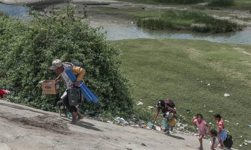 Ciudadanos venezolanos caminan tras bañarse en un canal de agua que pasa cerca a la población peruana de Aguas Verdes.