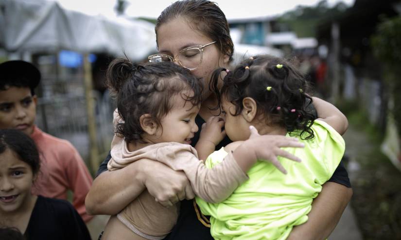 Dairana Moreno, migrante venezolana de 30 años, carga a su hija Salma Bracho (i) y otra menor, el 13 de octubre de 2022, en el pueblo de Bajo Chiquito (Panamá).