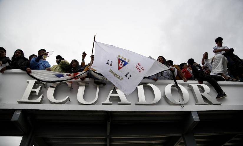 Hinchas de Liga sobre la puerta principal de la Universidad Central.