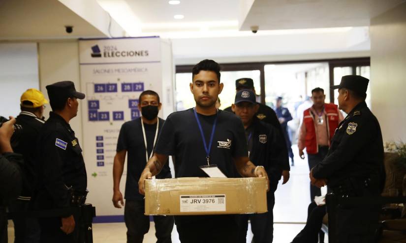 Personal del Tribunal Supremo Electoral y fiscales trasladan paquetes con material electoral en la sede donde se realiza el escrutinio final en San Salvador.