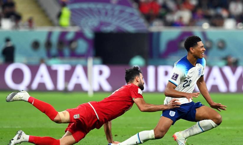 Ahmad Noorollahi (i) de Irán derriba hoy a Jude Bellingham de Inglaterra, durante un partido por el Grupo B del Mundial de Qatar 2022, en el estadio Khalifa International en Doha (Catar)
