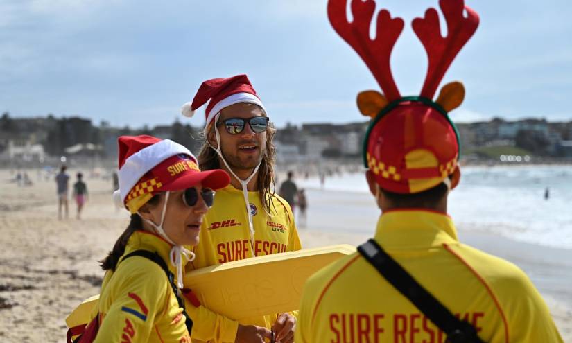Los salvavidas llevan gorros de Papá Noel y cuernos de reno mientras la gente celebra el día de Navidad en Bondi Beach, Sídney (Australia).