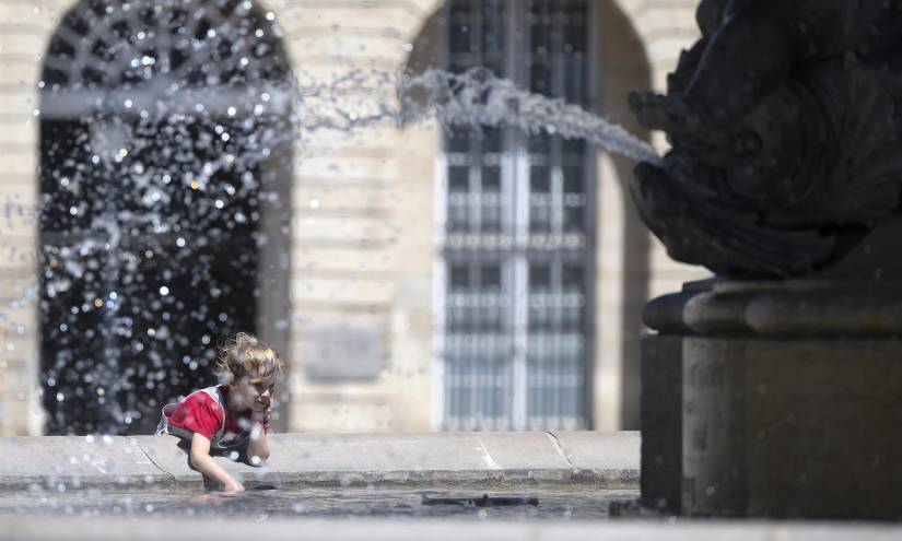 Un niño se refresca con agua de la fuente en la Place de la Bourse, en Burdeos.