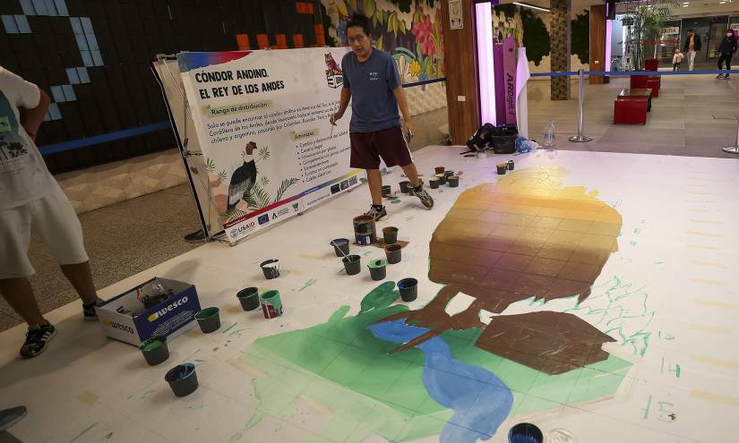 Artistas dibujan un condor en un centro comercial.