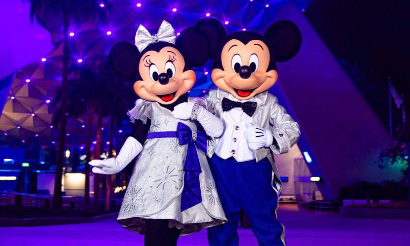 Fotografía cedida por Disney donde aparecen Mickey y Minnie Mouse con sus deslumbrantes trajes platino con ocasión de los 100 años de Disney mientras posan en la entrada del parque temático de EPCOT en Lake Buena Vista, Florida (EE. UU).
