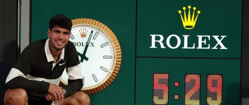 Carlos Alcaraz celebra junto al marcador que muestra la duración del partido tras ganar la final masculina más larga en la historia del Roland Garros.