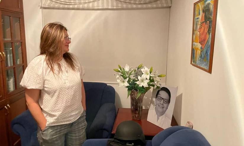 Verónica Sarauz junto a un chaleco antibalas, un casco y la foto de Villavicencio.