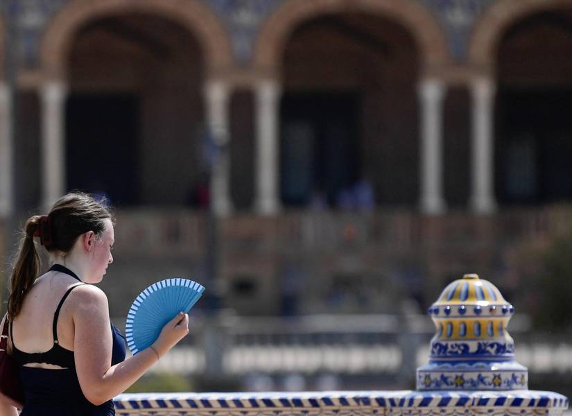 A woman refreshes with a fan during the extreme heatwave in Seville that exceeds forty degrees, in Seville on August 12, 2025. (Photo by CRISTINA QUICLER / AFP)