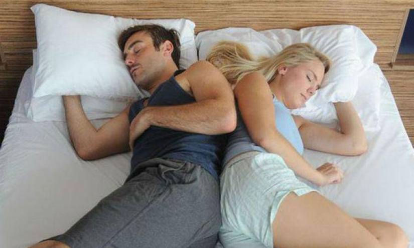 Una pareja durmiendo sin la colcha.