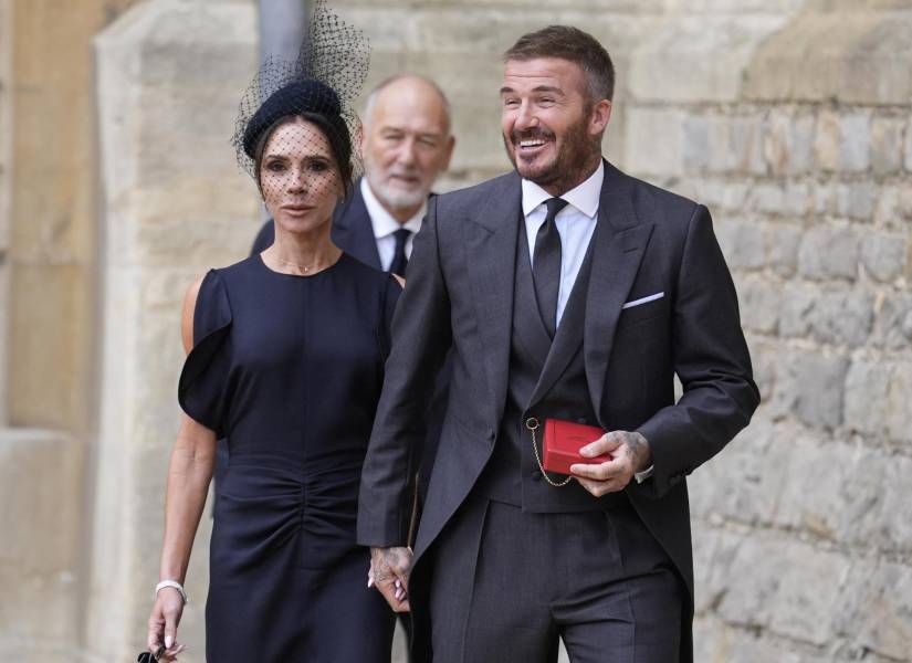 El exfutbolista inglés David Beckham (D) sale al patio seguido por su esposa, la cantante y diseñadora de moda Victoria Beckham (I), y su padre Ted (C), para posar ante los medios con su medalla después de ser nombrado Caballero (Knight Bachelor) por sus servicios al deporte y a la caridad durante una ceremonia de investidura en el Castillo de Windsor el 4 de noviembre de 2025.