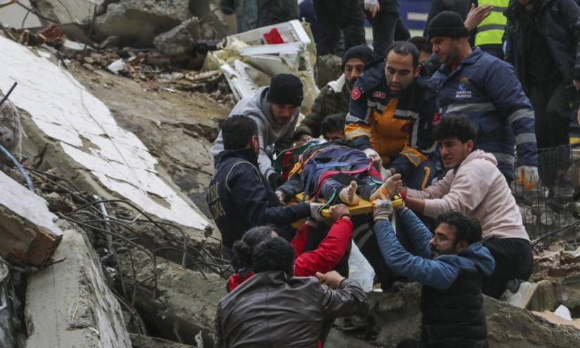 Gente y equipos de rescatistas trasladan a una persona en camilla desde un edificio derruido en Adana, Turquía, este lunes 6 de febrero.