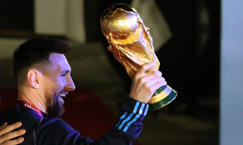 Lionel Messi saluda con el trofeo del Mundial de Fútbol Qatar 2022 a su llegada hoy, al Aeropuerto Internacional de Ezeiza.