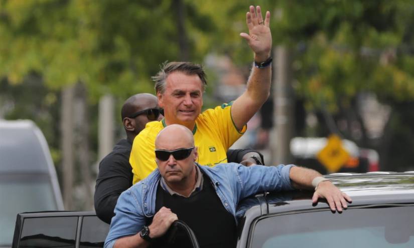 El presidente brasileño Jair Bolsonaro (c) saluda desde una caravana hoy, a su salida de un centro de votación en Río de Janeiro.