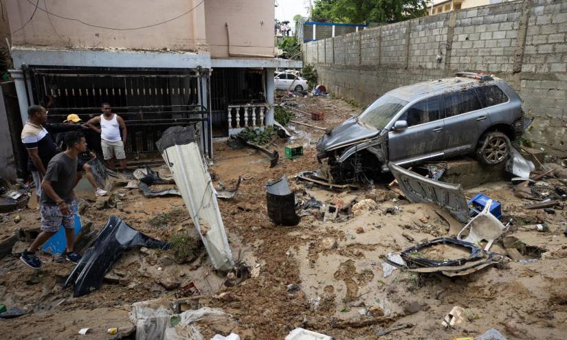 Imagen del 19 de noviembre.- Un hombre recupera pertenencias junto a varios vehículos que fueron arrastrados por la corriente, en Santo Domingo.