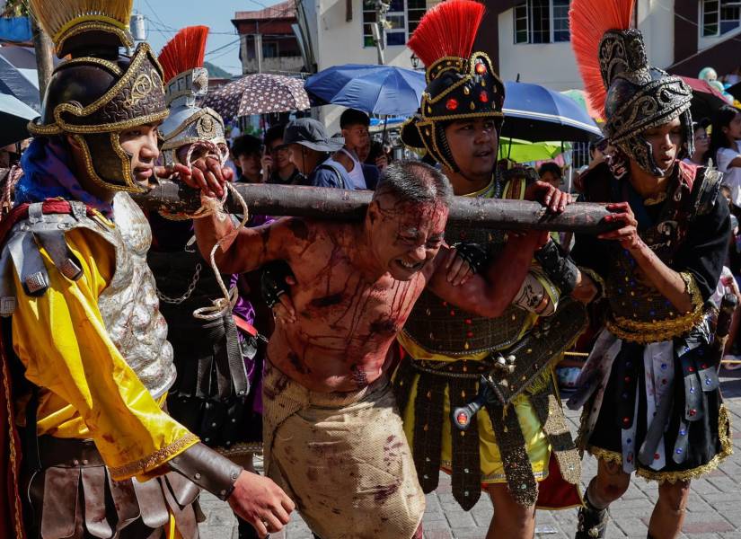 Personas observan como penitentes católicos representan la crucifixión y muerte de Jesucristo, en la ciudad de Paete, provincia de Laguna, Filipinas.