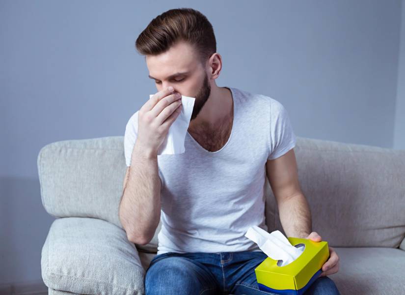 Joven sonándose la nariz.