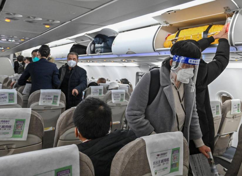 Un pasajero que lleva una careta y una mascarilla en medio de la pandemia de Covid-19 aborda un vuelo nacional en el Aeropuerto Internacional de Shanghái Pudong, en Shanghái.