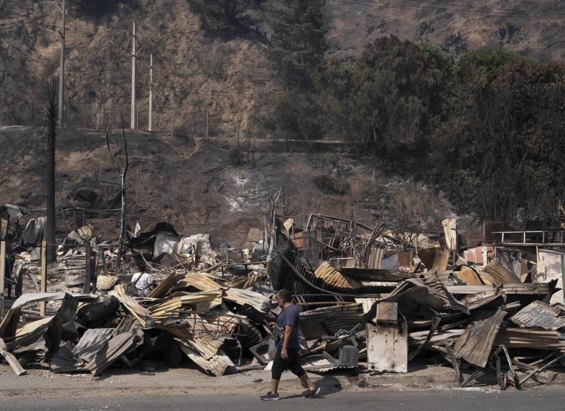 Un vecino camina frente a escombros de varias casas en El Salto, barrio que fue afectado por un voraz incendio, en Viña del Mar.