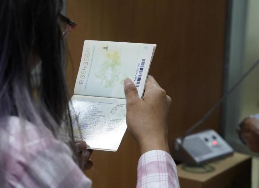 Imagen de una mujer consultando la información de un pasaporte ecuatoriano.