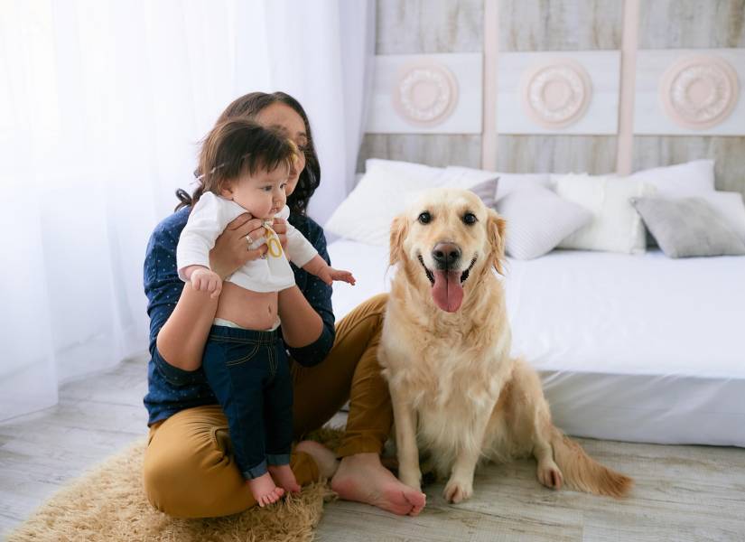 La madre abrazando a su hija y sentada cerca del perro.